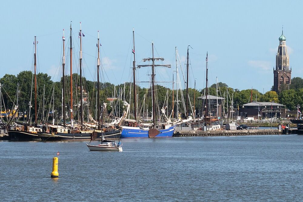 Haven van Enkhuizen met historische zeilschepen en een bakstenen toren met koepelspits op de achtergrond